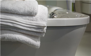 Ein Stapel weißer Handtücher auf einer Badewanne. 