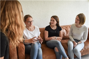 Vier junge Frauen besprechen sich sitzend