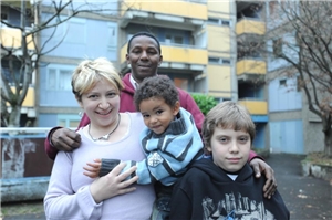 Ein vierköpfige Patchworkfamilie steht vor einem Mehrfamilienhaus