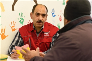 Flüchtlingshelfer und Mann sprechen gemeinsam über ein Ausweisdokument