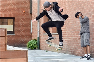 Zwei Jugendliche auf Platz mit Skateboard 