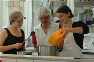 zwei Jugendliche mit einer Frau beim Kochen