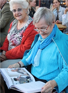 Seniorin blättert lächelnd im Kochbuch
