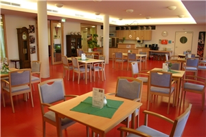 Caféteria Die Caféteria im Caritas-Altenzentrum St. Elisabeth - ein wohnlicher, einladender Raum mit einem Fußboden in einem warmen Rotton, Holzmöbeln und hellen Wänden.