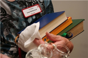 Eine ehrenamtliche Mitarbeiterin hält Bücher für den Gottesdienst in der Hand. Eine ehrenamtliche Mitarbeiterin hält Bücher für den Gottesdienst in der Hand.