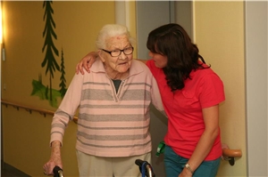 Eine Mitarbeiterin des Caritas-Altenzentrums St. Barbara hilft einer Bewohnerin beim Gehen. 