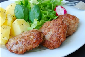 Mittags gibt es verschiedene Menüs zur Auswahl. Ein Teller mit Frikadellen, Kartoffeln und Salat.
