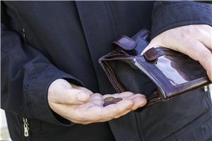 Ein Mann öffnet eine Brieftasche, in der sich aber nur ein paar Münzen befinden. 