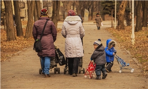 2 Frauen mit Kinderwagen, 2 Kinder mit Buggy auf winterlichem Weg im Park