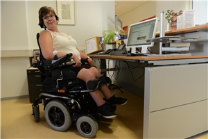 Julia_Mühlebach_1 Frau sitzt in Rollstuhl hinter Empfangstresen