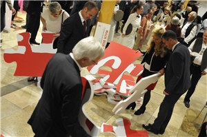 Jubiläum 19 Personen legen ein großes Puzzle