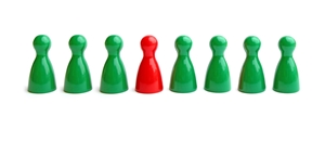 grüne Spielfiguren stehen in einer Reihe, in der Mitte eine rote Spielfigur