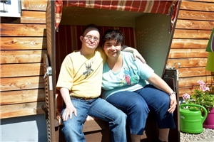 Mann und Frau mit Beeinträchtigung sitzen nebeneinander im Starndkorb