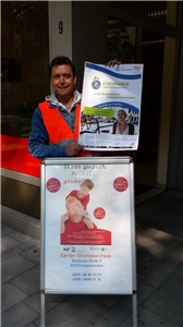Uwe Steingräber posiert mit seinem Fahrrad vorm NeuStaftTreff der Caritas und hält ein Stadtradel-Poster in der Hand.