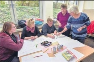 Fünf Frauen um einen Tisch mit ausgebreiteten Zeichnungen