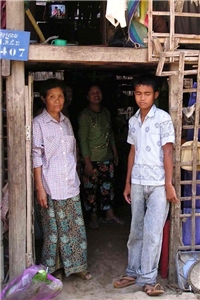 Junge und Frau stehen am Eingang einer Hütte