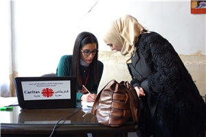 Eine Frau mit Kopftuch wird von einer Mitarbeiterin der Caritas Syrien als Bedürftige registriert