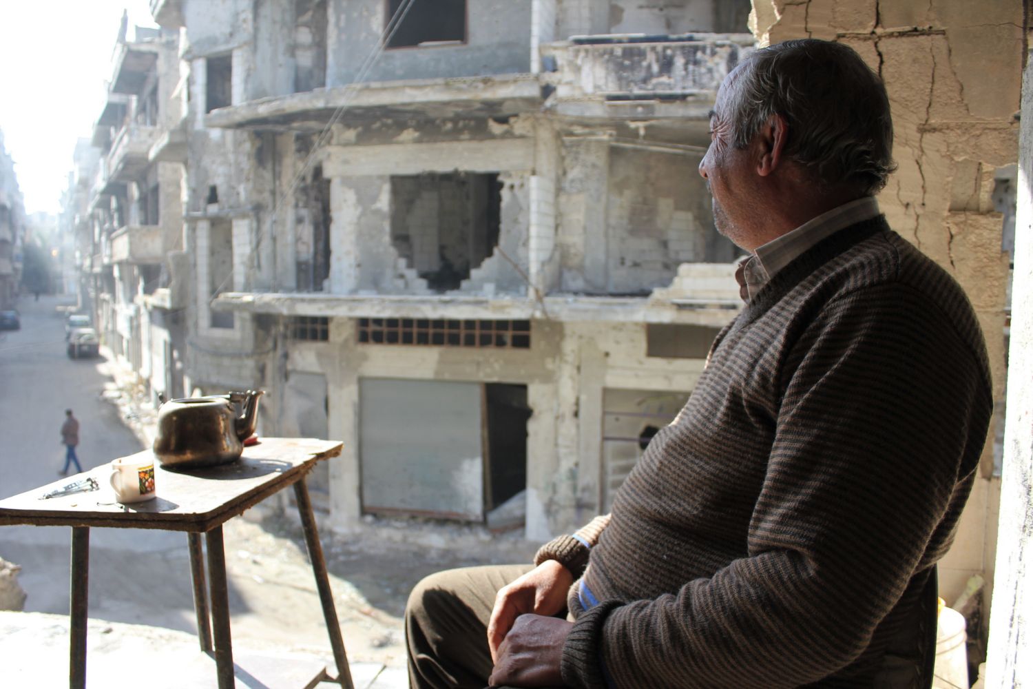 Ein Mann sitzt in einem zerstörten Wohnhaus in Syrien und trinkt Tee