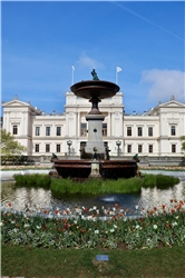 Springbrunnenanlage, im Hintergrund ein helles repräsentatives Gebäude