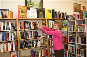 Frau räumt Bücher in ein Regal