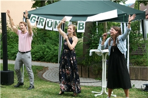 Drei junge Menschen singen im Freien.