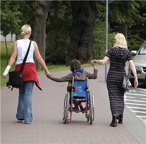 Schulbegleiter mit einem Jugendlichen im Rollstuhl auf dem Weg zur Schule