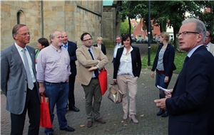Das Foto zeigt eine Gruppe von Menschen vor einer Kirchenmauer, denen eine Person etwas erklärt.