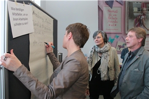 Workshop beim Fachwissen zum Frühstück Drei Personen beschriften ein Plakat.