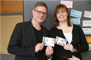 Die Digitalisierungsreferenten des Stadt-Caritasverbandes Münster und des Diözesancartitasverbandes Münster halten zwei Postkarten in der Hand, mit der sie für die Onlineberatung werben. 