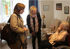 Zwei Frauen sprechen mit einer älteren Dame im Rollstuhl