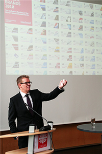 Das Bild zeigt einen Referenten vor einer Projektion mit vielen kleinen Logos Das Bild zeigt einen Referenten vor einer Projektion mit vielen kleinen Logos