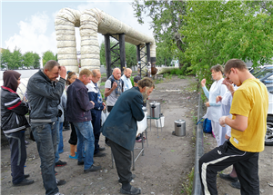 Russische Obdachlose stehen mit Mitarbeiterinnen der Caritas vor einer provisorischen Essenausgabe hinter einem Bahnhofsgelände und beten