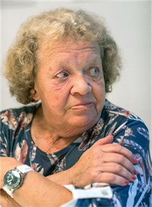 Eine Seniorin mit verschränkten Armen, die zur Seite blickt