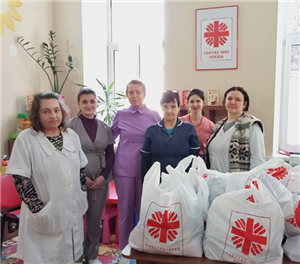 Sechs Mitarbeitende der Caritas-Spes in Odessa, die vor einem Tisch mit Spendentüten stehen