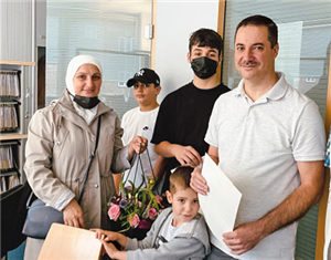 Basel und Ramia Al Shoueb stehen mit ihren drei Kindern zusammen in einem Büro. Basel Al Shoueb hält dabei eine Urkunde in den Händen.