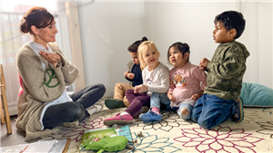 Nicole Weyer sitzt mit zwei Jungen und zwei Mädchen in der Kita Saltkrokan in Essen auf einem Teppich