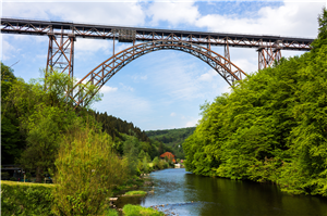 Die Müngstener Brücke (stählernde Bogen-/Eisenbahnbrücke) in Solingen, unter der die Wupper durchfließt. Die Uferseiten sind dicht bewachsen, im Hintergrund ist das Restaurant 'Haus Müngesten' zu sehe
