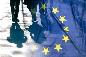 Eine Fotomontage, bei der ein Foto von Menschen, die über einen gepflasterten Weg laufen, in eine Foto einer wehenden Europaflagge übergeht