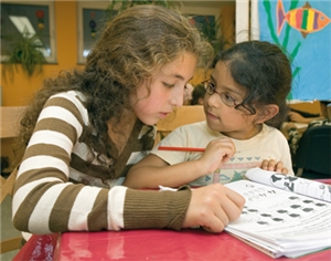 Ein Mädchen hilft einem jüngeren Mädchen bei den Hausaufgaben