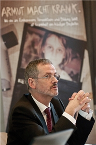 Der Caritas-Präsident Prälat Dr. Peter Neher. Im Hintergrund befindet sich ein Rollup der Caritas-Jahreskampagne 2012. 