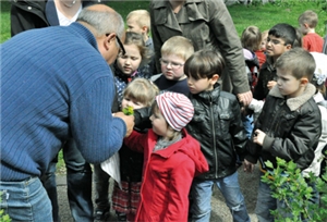 Sozialarbeiter Pietro Basile zeigt einer Gruppe Kinder und einigen Erwachsenen eine Pflanze
