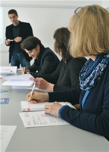 Drei Teilnehmer einer Veranstaltung der EU-Fördermittelberatung. Im Hintergrund hält der Referent Heiko Jungbecker eine Präsentation.