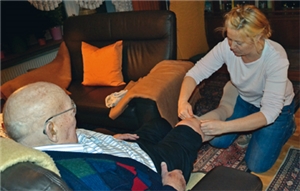 Katrin Piorunek zieht einem Patienten die Stützstrümpfe über