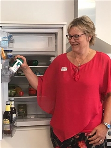 Seniorenlotsin stellt Notfalldose in Kühlschrank Eine Seniorenlotsin stellt eine Notfalldose in den Kühlschrank