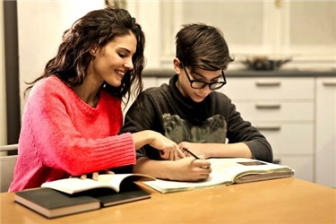 Frau hilft Jugendlichem bei den Hausaufgaben