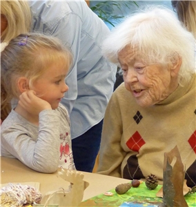 Ein kleines Mädchen und eine Seniorin gestalten gemeinsam Fühlbilder