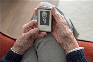 Eine Seniorin hält ein altes Foto in ihren Händen