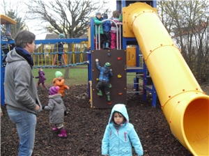 Außenspielgerät mit kletterneden Kindern und Erwachsenen, die aufpassen.