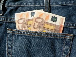 Überschuldete Spielsüchtige benötigen Hilfe Bild einer Jeans Hosentasche, aus der zwei Fünfzig Euroscheine rausschauen.