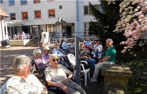 Bild 3 Gemütliche Runde vor dem Haus Bewohner und Gäste sitzen gemeinsam in fröhlicher Runde vor dem Haus